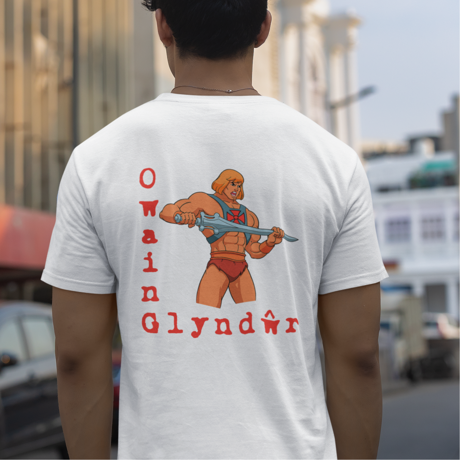 Person wearing a white t-shirt with Owain Glyndwr design on the back, standing on a street.