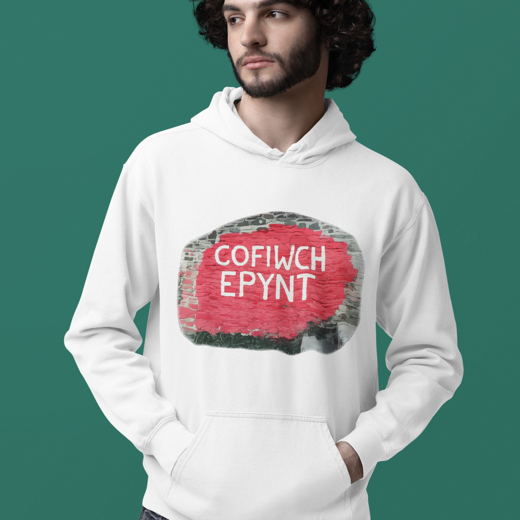 Man wearing a white hoodie with a Cofiwch Epynt design on a green background