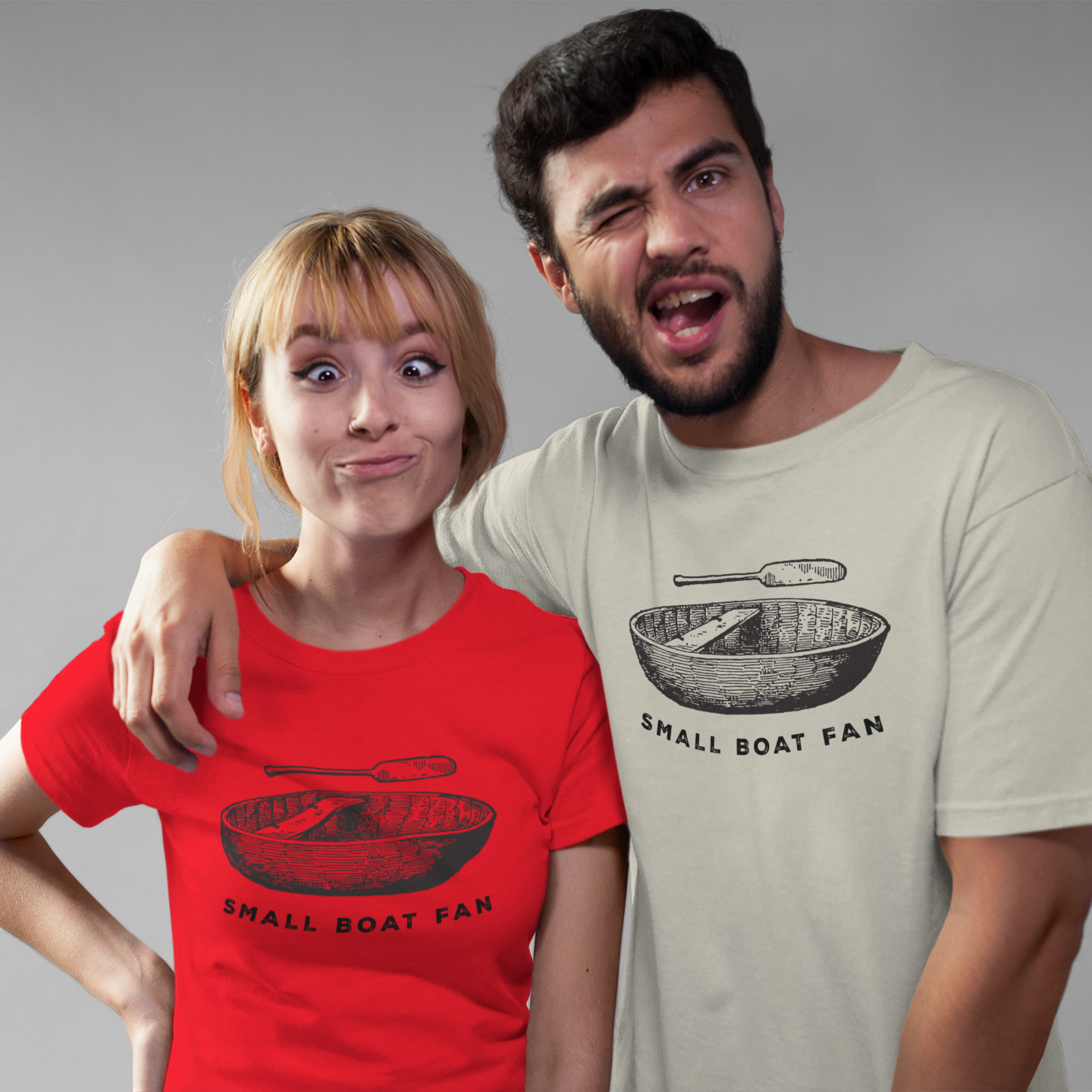 Two people wearing t-shirts with 'Small Boat Fan' design on a gray background