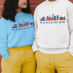 Two models wearing matching sweatshirts and cargo pants standing against a red brick wall. The person on the left wears a light blue sweatshirt and mustard yellow pants, while the person on the right wears a white sweatshirt and mustard yellow pants.