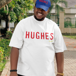 Person wearing a white shirt with 'HUGHES' printed on it, standing outdoors.
