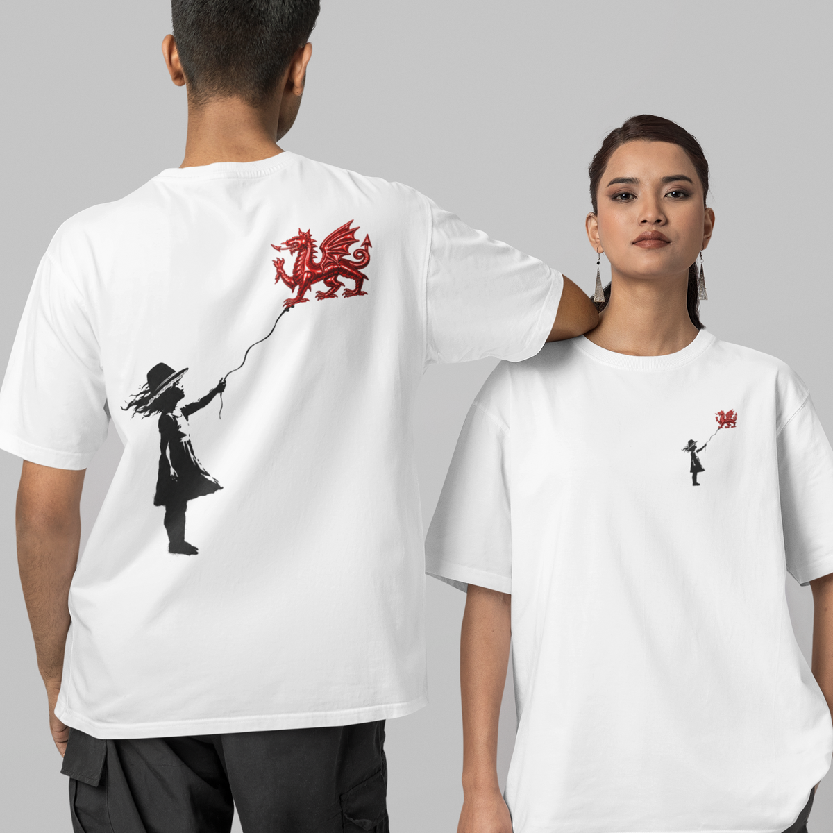 Two models wearing white graphic t-shirts against a solid gray background. The model on the left is shown from the back, wearing a white t-shirt with a large black silhouette of a person holding a red balloon.