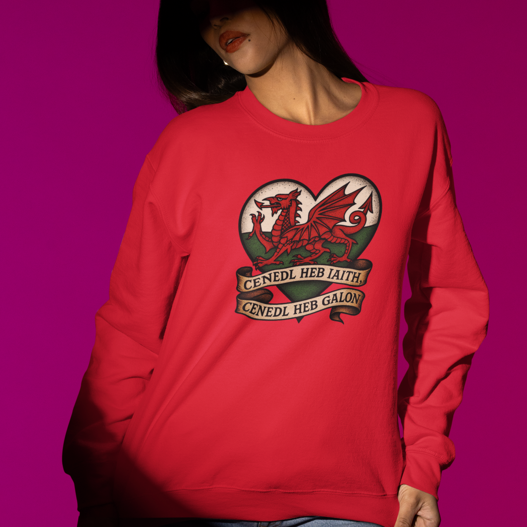 Person wearing a red sweatshirt with a dragon design on a pink background