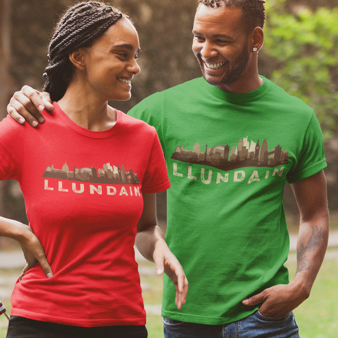 Two people wearing red and green t-shirts with 'Llundain' text, standing outdoors.