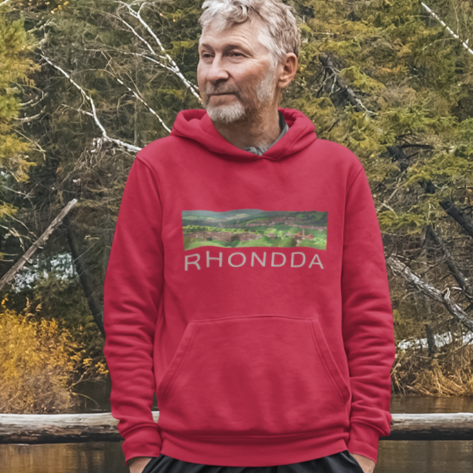 Person wearing a red hoodie with 'RHONDDA' logo standing on a wooden bridge over a lake with trees in the background.