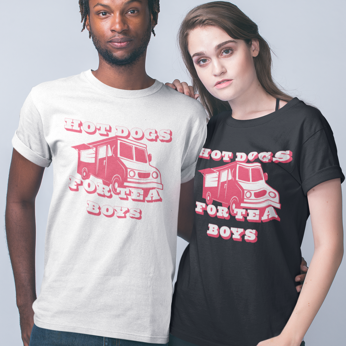 Two models wearing custom graphic t-shirts with the text 'HOT DOGS FOR TEA BOYS' and a red truck illustration, shown against a plain light gray studio background.