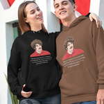 A man and a woman standing outdoors in front of a modern white and red geometric building, wearing matching custom-printed hoodies. The woman wears a black hoodie, and the man wears a brown hoodie, both featuring a graphic print of a man's face with the text 'I'm not a monster, I'm just a normal guy who does normal stuff'.
