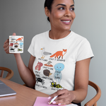 Woman holding a mug with animal illustrations, wearing a matching t-shirt, sitting at a table.