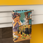 A kitchen towel with a retro-style illustration of a woman cooking over a pot of food, hanging from a metal rack on a white cabinet in a kitchen setting.