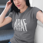Woman wearing a gray t-shirt with 'ARAF' printed on it, sitting on a couch.