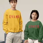 Two people wearing 'EVANS' sweatshirts in yellow and green, sitting on geometric blocks.