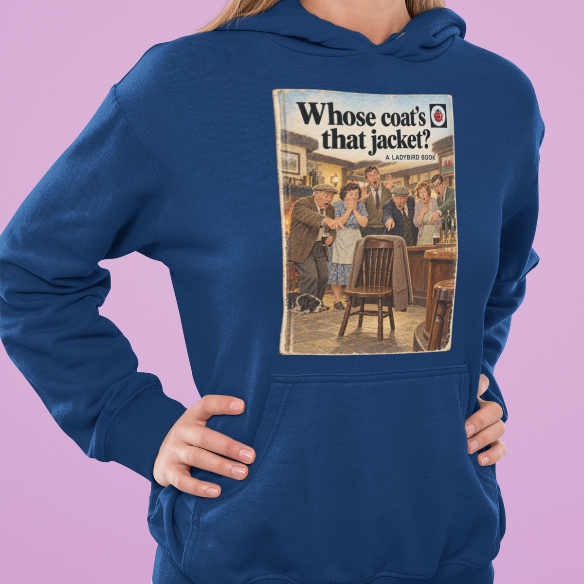 A woman modeling a royal blue hoodie with a vintage-style magazine cover graphic on the chest reading 'Whose coat's that jacket?'. The background is a solid lavender-purple color.