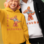 Two models posing together in a colorful studio setting, wearing He-Man themed hoodies. The model on the left wears a bright yellow hoodie, and the model on the right wears a white hoodie under an open black denim jacket.