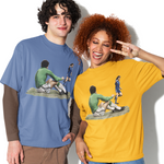 Two models posing in oversized graphic t-shirts. The model on the left wears a dusty blue t-shirt with a brown long-sleeve layer underneath, paired with brown shorts.