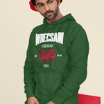 Man wearing a green hoodie with Wrecsam and graphics, sitting on a red box against a beige background