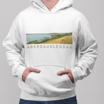 A man wearing a white pullover hoodie with a rectangular landscape graphic on the chest and the text 'ABERDAUGLEDDAU' printed below it, paired with blue jeans against a plain gray studio background.