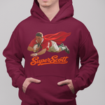 A man wearing a maroon hoodie with a graphic of a rugby player in a red cape and the text 'Super Scott' in orange, paired with blue jeans against a solid gray background.