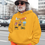 Man wearing a yellow hoodie with cartoon designs and orange pants standing on a street.