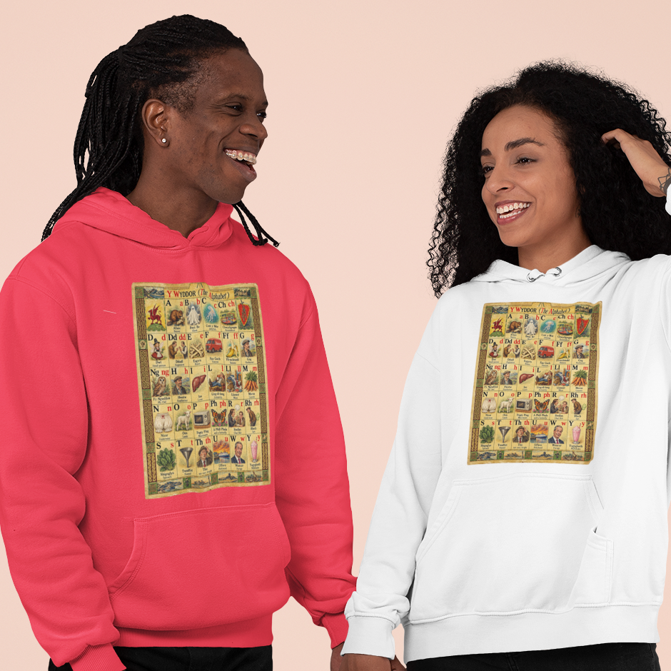 Two models holding hands, one wearing a bright pink hoodie and the other wearing a white hoodie, both featuring a large vintage-style illustrated graphic on the chest, set against a solid pale peach background.
