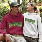 A man and a woman posing in a wooded outdoor setting, both wearing matching white and maroon hoodies with a landscape graphic and the text 'RHOSLLANERCHRUGOG'.