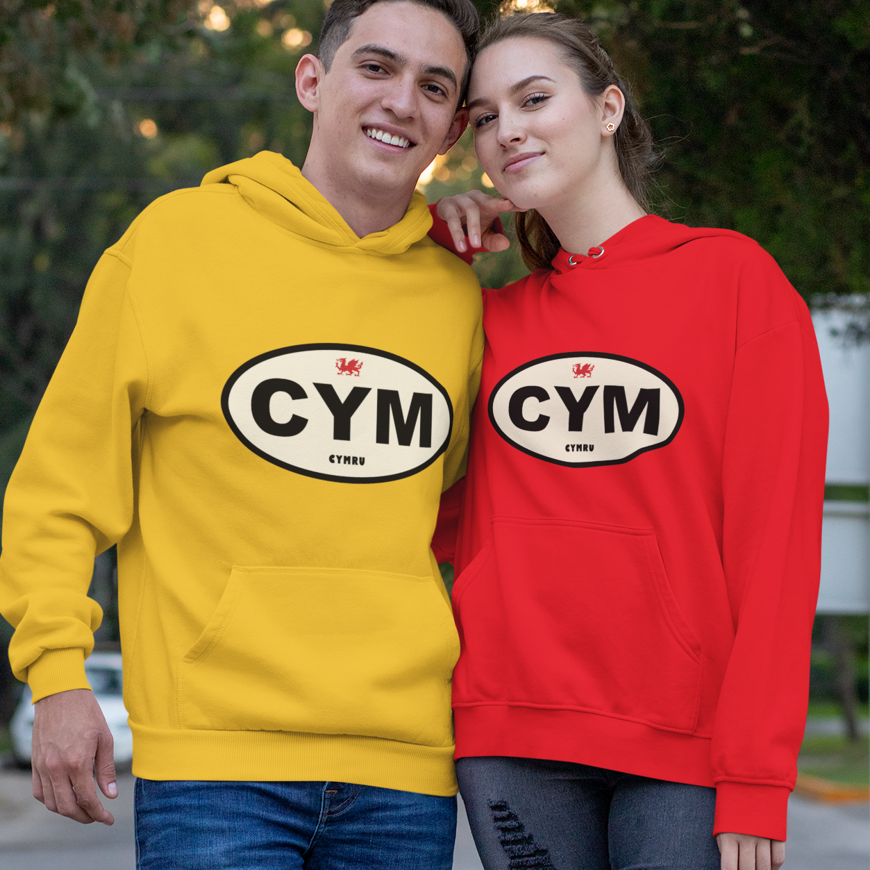 Two people wearing yellow and red hoodies with 'CYM' logo outdoors.