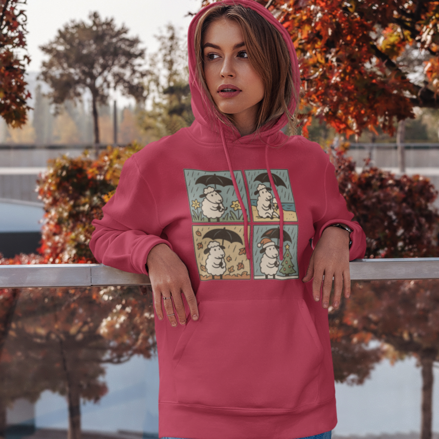 Person wearing a pink hoodie with graphic design, standing outdoors near trees with autumn foliage.