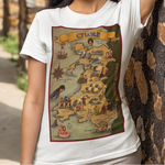 A woman posing outdoors against a stone wall, wearing a white crewneck t-shirt with a vintage-style map graphic of Wales on the front, paired with beige trousers.