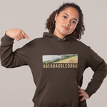 Person wearing a brown hoodie with a graphic and text, pointing at the design.