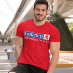 Man wearing a red t-shirt with a brand logo, standing outdoors on a city street.
