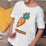 A young boy wearing a white t-shirt with a cartoon carrot graphic and the word 'MORON' printed below it, standing in a living room setting.