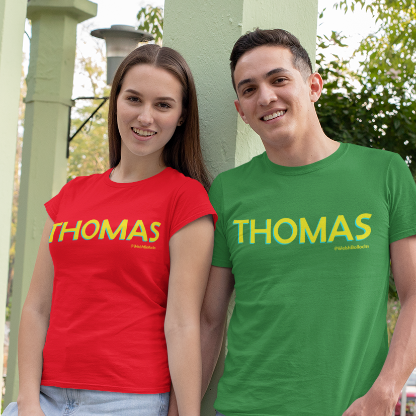 Two people wearing red and green 'THOMAS' t-shirts in a park setting.