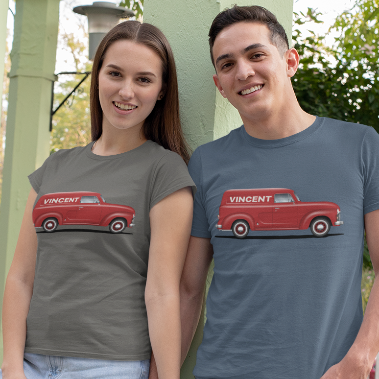 A man and a woman standing side-by-side wearing matching graphic t-shirts. The woman's t-shirt is a muted gray-green with a red vintage truck graphic, and the man's t-shirt is a slate blue with the same red truck graphic.