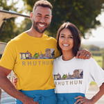 A man and a woman standing outdoors in front of a vehicle, wearing matching aprons and T-shirts featuring a Rhuthun skyline graphic. The man wears a mustard yellow shirt and the woman wears a white shirt, both with blue aprons.