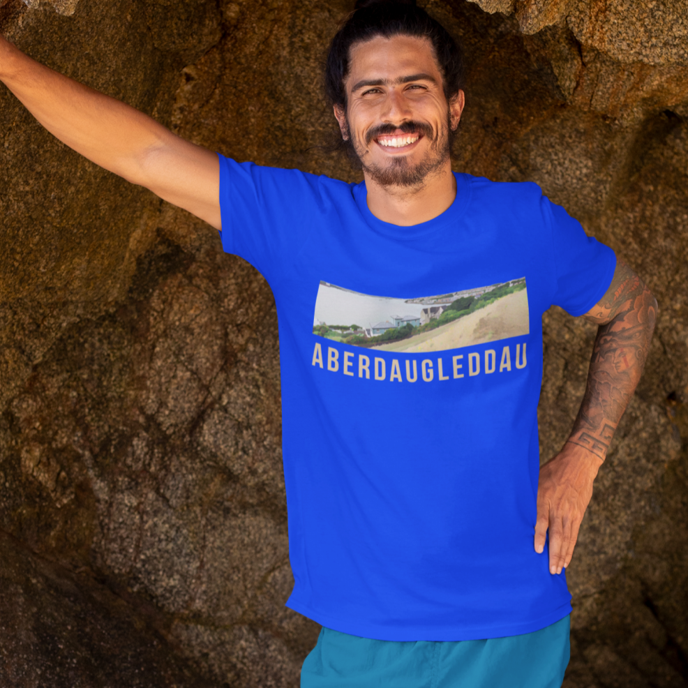 Man standing in a natural rock formation wearing a blue t-shirt with a graphic design.