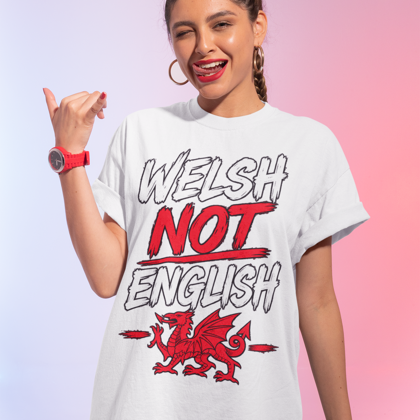 A woman modeling a white graphic t-shirt with the text 'WELSH NOT ENGLISH' and a red dragon illustration, set against a pink and purple gradient background.