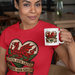 Woman wearing a red t-shirt with a dragon design, holding a mug in a casual setting.