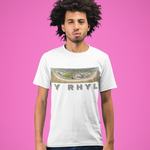 A man with dark curly hair wearing a white graphic t-shirt and dark blue jeans, standing against a solid pink background. The t-shirt features a colorful stadium graphic above the text 'Y RHYL'.