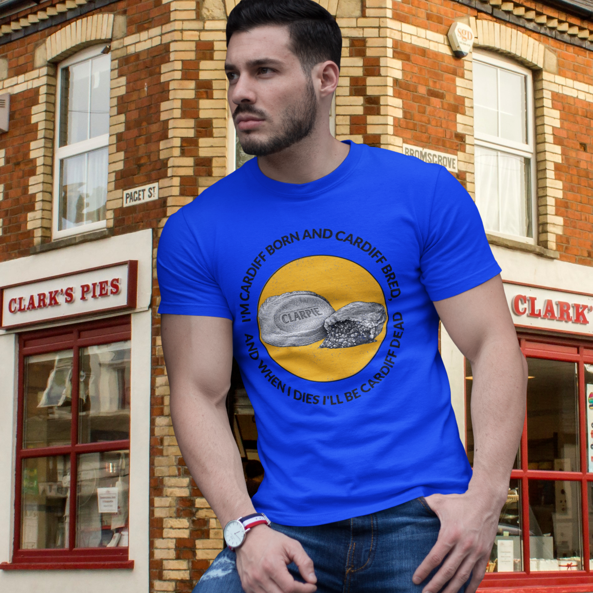 Man wearing a blue t-shirt with a graphic design in front of a brick building.
