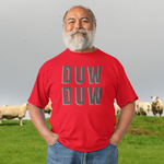 Man wearing a red shirt with 'DUW DUW' text, standing in a field with sheep.